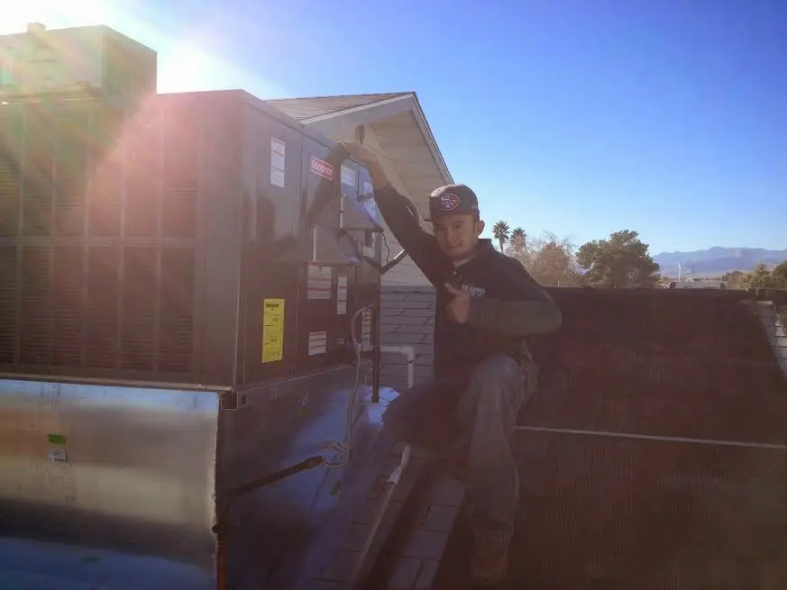 HVAC technician performing AC Tune-Up on a rooftop unit in Kaser