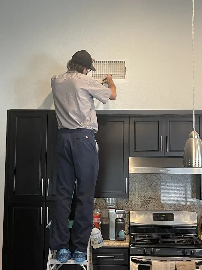 Technician inspecting an air vent during HVAC service in Kaser